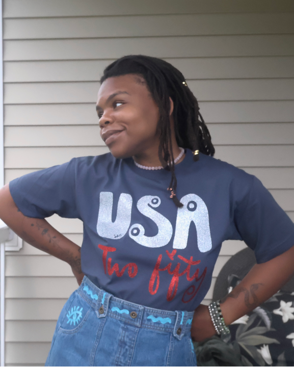 Person wearing a 'USA' t-shirt on a porch with a grassy field in the background
